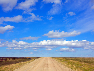 Fototapeta na wymiar Beautiful summer road and white clouds in the tundra