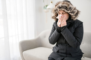 Woman With Warm Clothing Feeling The Cold Inside House on the sofa she having flu and using tissue