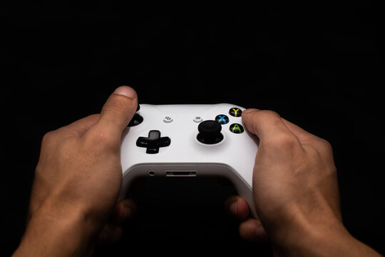 Man playing video games, holding control in hand with black background. Banner for video games and games with space for text.