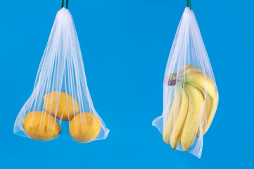 Bananas and lemons in a reusable eco friendly net bags on a blue background.