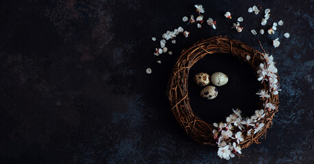 Easter background with Easter eggs and spring flowers. Eggs in nest on dark vintage wooden background.