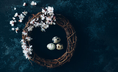 Easter background with Easter eggs and spring flowers. Eggs in nest on dark vintage wooden background.