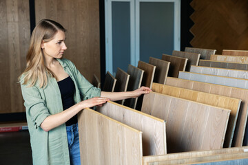 woman choosing laminate floor design from samples in flooring store