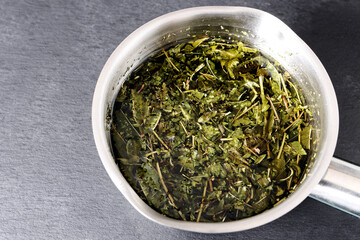 Fototapeta na wymiar Lemon verbena leaves in water in metal pot to be boiled. Verbena tea.