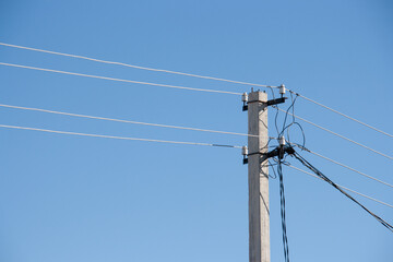 Power line post with with white insulators and wires on a background of blue sky