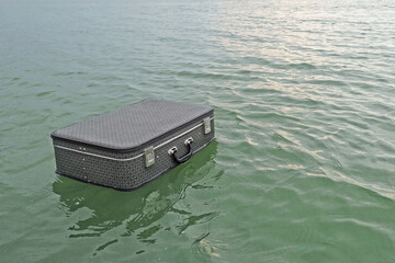  Suitcase in hand above the water when crossing the river. traveling by water