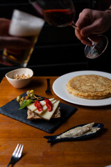 Spanish tapas on a bar table with people making a toast on second term on a bar background.