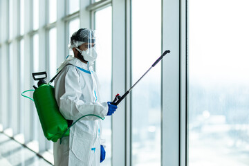 People in virus protective suits and mask disinfecting buildings of coronavirus with the sprayer