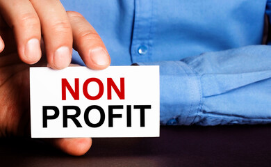 NON PROFIT is written on a white business card in a man's hand. Advertising concept