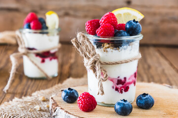 Yogurt with berries and cereals in a glass on a rustic wooden table