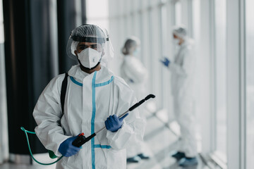 Portrait of doctor in white safety protective uniform ready desinfect covid-19 contamination...