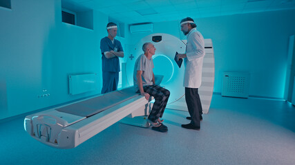 Male doctors preparing elderly man for CT scan