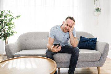 A sad man using smartphone at home