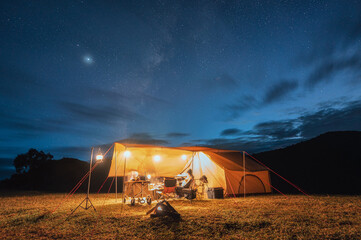 Tourists in yellow tent camping on hill with milky way in the night sky - obrazy, fototapety, plakaty