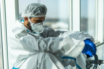 Asian man Doctor in protective hazmat PPE sad, tire and despair. Medical staff in clean suit. Male practitioner.
