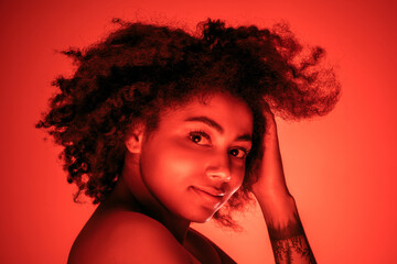 Dancing. Beautiful african-american woman's portrait isolated on red studio background in neon, monochrome. Concept of human emotions, facial expression, sales, ad, fashion and beauty.