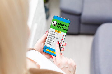 woman holding a mobile phone with sports betting website in the screen.