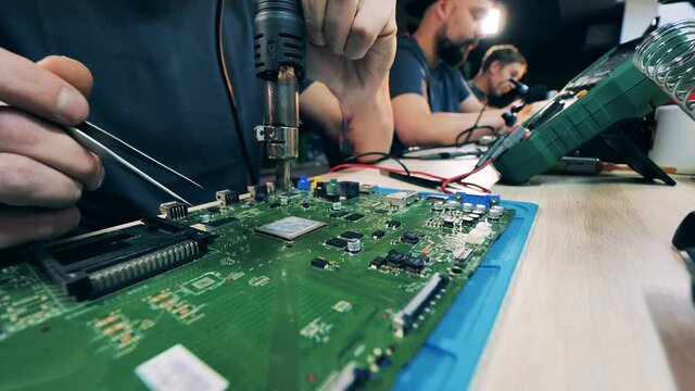 Male specialist is preparing to solder a laptop circuit