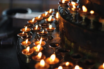 Buddhist Old Altar Candles at Religious 108 Butter Lamp Festival in Temple Monastery. Beautiful Tranquil Scenic View of Oil Lamps and Swaying Flame for Praying  - obrazy, fototapety, plakaty