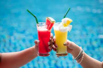A man and a woman were beating a glass of a smoothie by the hotel pool. The concept of travel and leisure in the holidays