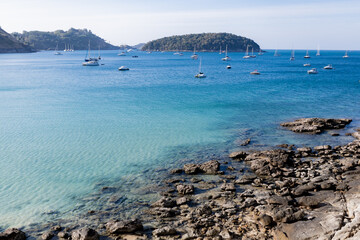 Blue sea fill with many Yachts with foreground of rocks.