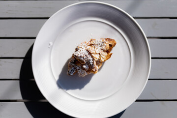 Croissant almond on the white plate with rim light.