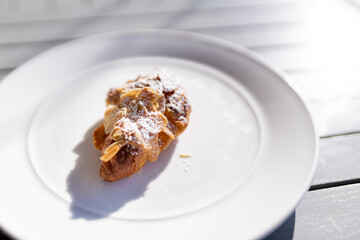 Croissant almond on the white plate with rim light.