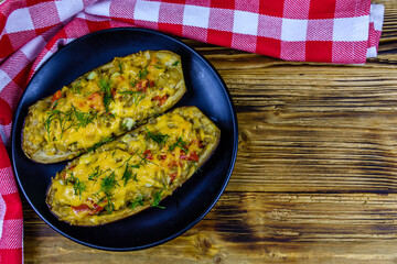Plate with baked stuffed eggplants on a wooden table. Top view