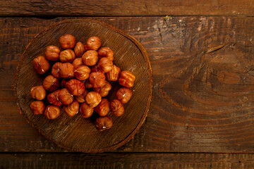 Hazelnuts scattered on a wooden round board.