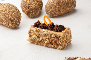 cake filled and decorated with chocolate next to whole grain breads with seeds and sesame on top, pastry in a studio
