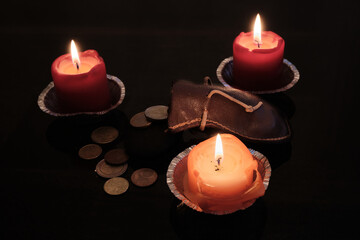 Euro coins dropped from the leather bag near the candles in dark room