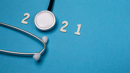 Close up black modern stethoscope with reflection on blue background with copy space. Medical nurse or doctor equipment object. Medicine healthcare concept. Numbers wooden 2021 banner