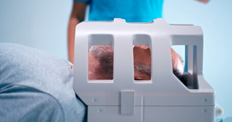 Crop black doctor preparing aged man for brain MRI
