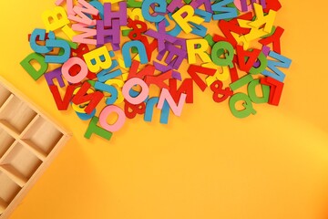 Pile of colorful block letters with the wooden compartment on the yellow background
