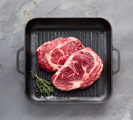 Beefsteak with spices and grill skillet on stone background