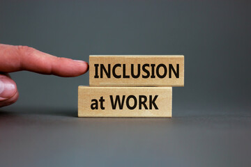 Inclusion at work symbol. Wooden blocks with words 'Inclusion at work' on beautiful grey background. Businessman hand. Business, inclusion at work concept. Copy space.