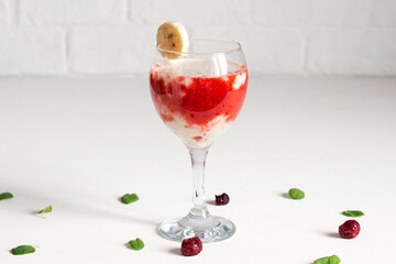 Banana smoothie with sweet berry sauce in a beautiful wine glass.
