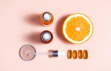 Fotobehang Anti aging facial serums with pipette, orange and omega-3 vitamin on pink background. Q 10, retinol, vitamin C, collagen, hyaluronic acid and salicylic acid face serum, top view composition © Tijana