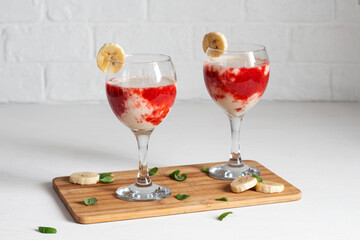 Two glass with berry banana milkshake.