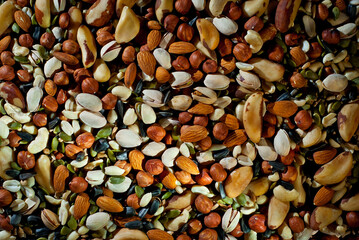 Many types of nuts close up. Textures of different nuts. Nuts are dumped in a pile. Contrasting dramatic light as an artistic effect.