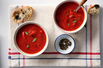 Tomato soup in a white bowl on white background. Top view. Copy space