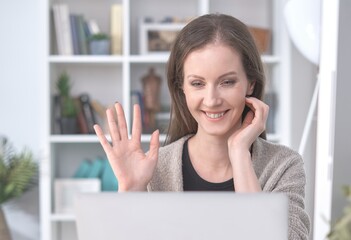 Happy white woman smiling, having video chat with friends or family, having business meeting via video call, conference at home, using laptop computer.