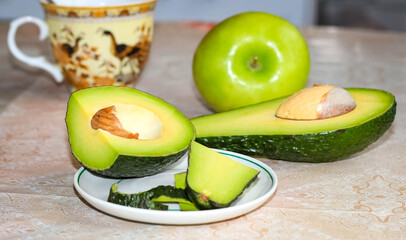Sliced avocado and green apple on the kitchen table. Proper nutrition.