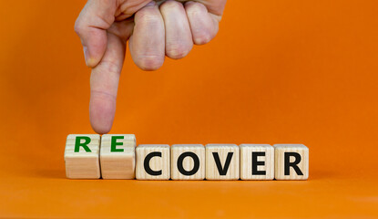 Time to recover symbol. Businessman turns wooden cubes and changes the word 'cover' to 'recover'. Beautiful orange background. Business, cover or recover concept. Copy space.