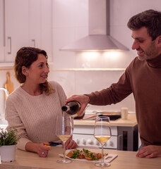 Romantic couple is cooking in the nordic vintage style kitchen. A handsome man and an attractive young woman are having fun together while having tapas and drinking wine. Healthy lifestyle concept.
