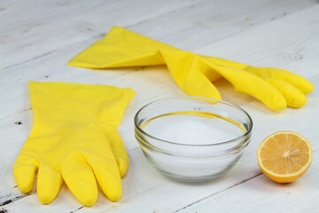 Crystalline citric acid in a bowl, good for cleaning.  Rubber gloves and lemon cut in half on the...