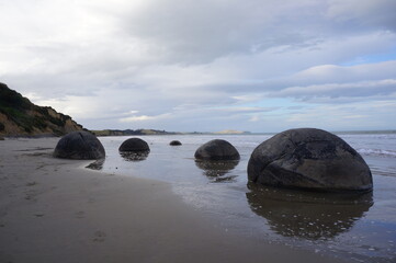 Fototapeta na wymiar The Moeraki Boulders are unique large round stones lying along of Koekohe Beach in New Zealand
