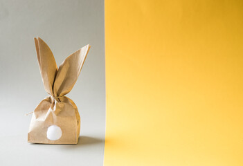 Easter bunny paper gift egg wrapping DIY idea on colorful background. Minimal easter concept, flat...