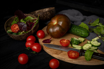 Ingredients for making salad on rustic black board background. Vegetable salad in bowl, tomato, cucumber, tomatoes kumato. Healthy, clean eating concept. Vegan or gluten free diet