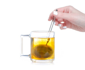 Metal tea strainer with glass cup of tea in hand on white background isolation
